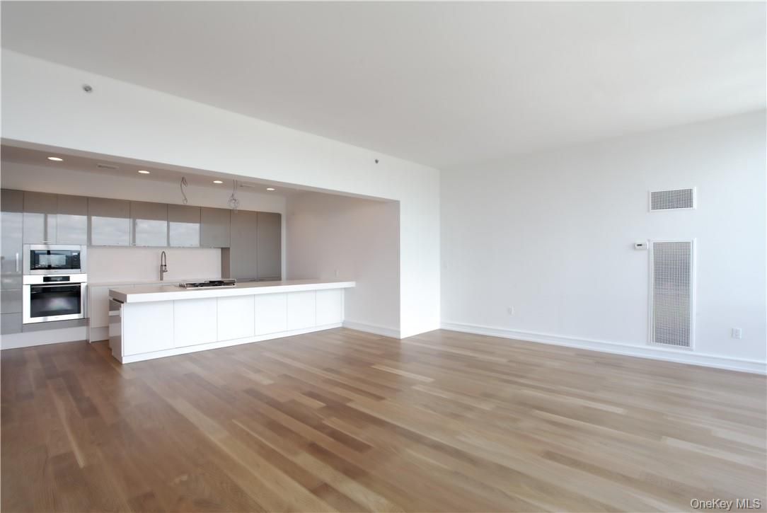 Empty room, Interior, Kitchen, Recessed Lighting, Stainless Steel Appliances, Wood Texture Flooring
