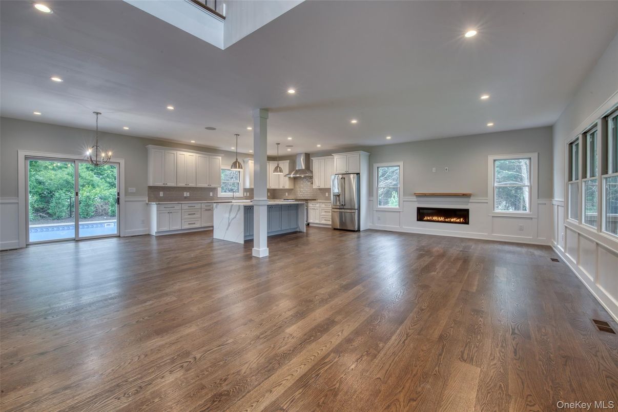 Empty room, Fireplace, Interior, Kitchen, Pendant Lights, Recessed Lighting, Stainless Steel Appliances, Wood Texture Flooring