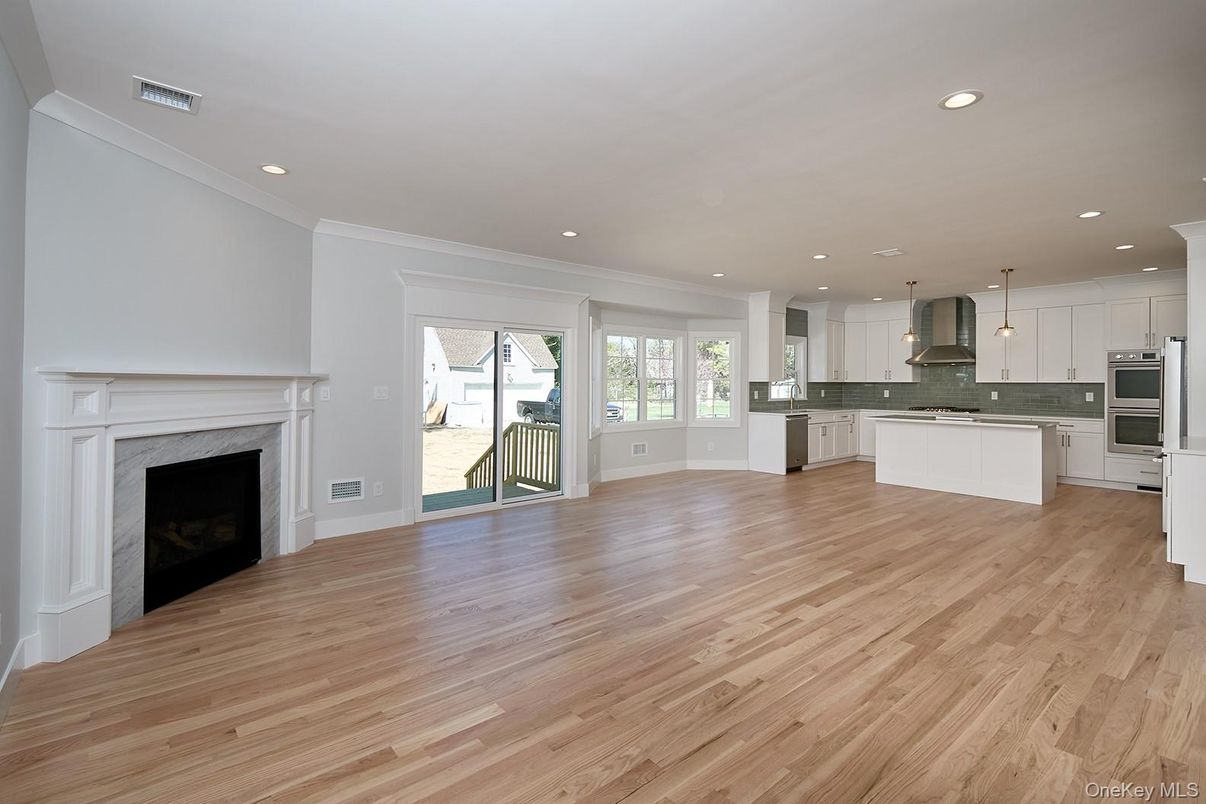 Empty room, Fireplace, Interior, Kitchen, Pendant Lights, Recessed Lighting, Stainless Steel Appliances, Wood Texture Flooring