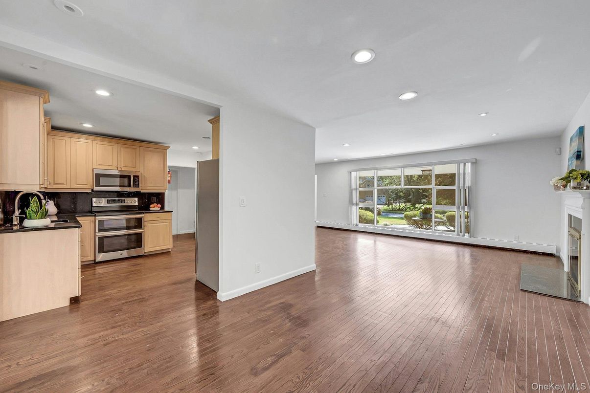 Empty room, Fireplace, Interior, Kitchen, Recessed Lighting, Stainless Steel Appliances, Wood Texture Flooring