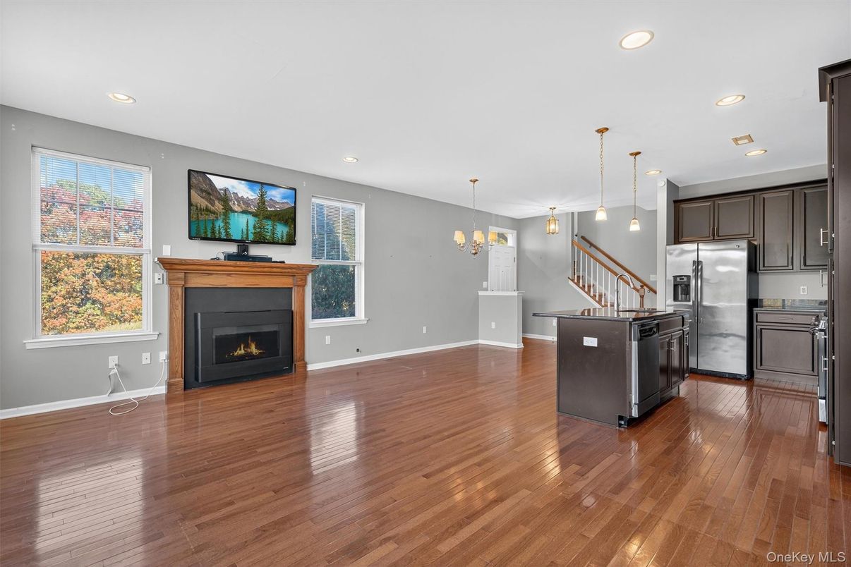 Chandelier, Empty room, Fireplace, Interior, Kitchen, Pendant Lights, Recessed Lighting, Stainless Steel Appliances, Wood Texture Flooring