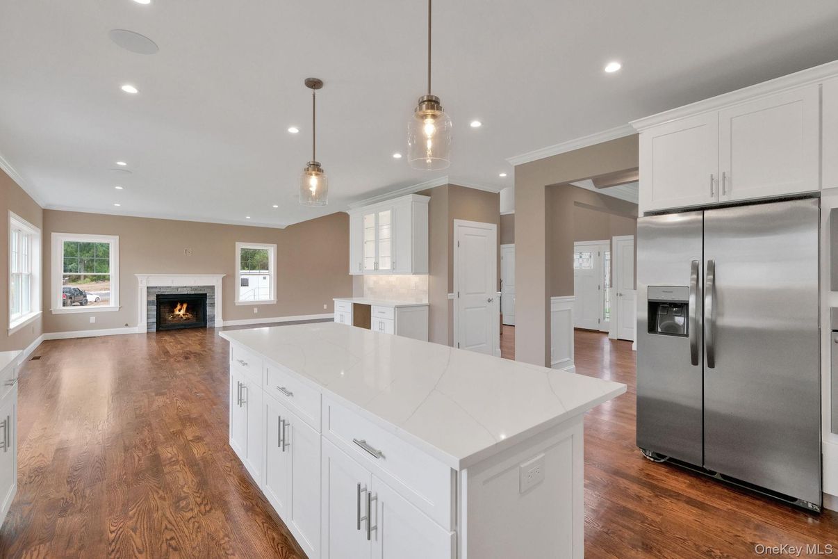 Empty room, Fireplace, Interior, Kitchen, Pendant Lights, Recessed Lighting, Stainless Steel Appliances, Wood Texture Flooring