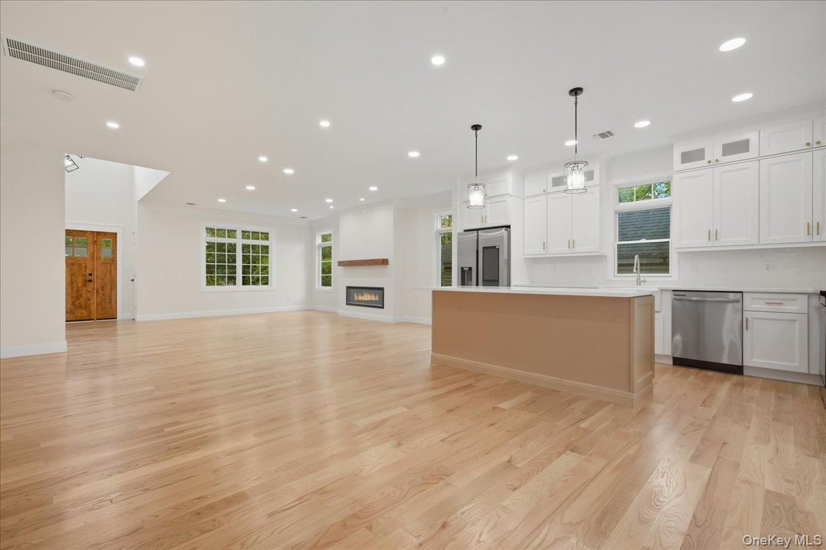 Empty room, Fireplace, Interior, Kitchen, Pendant Lights, Recessed Lighting, Stainless Steel Appliances, Wood Texture Flooring