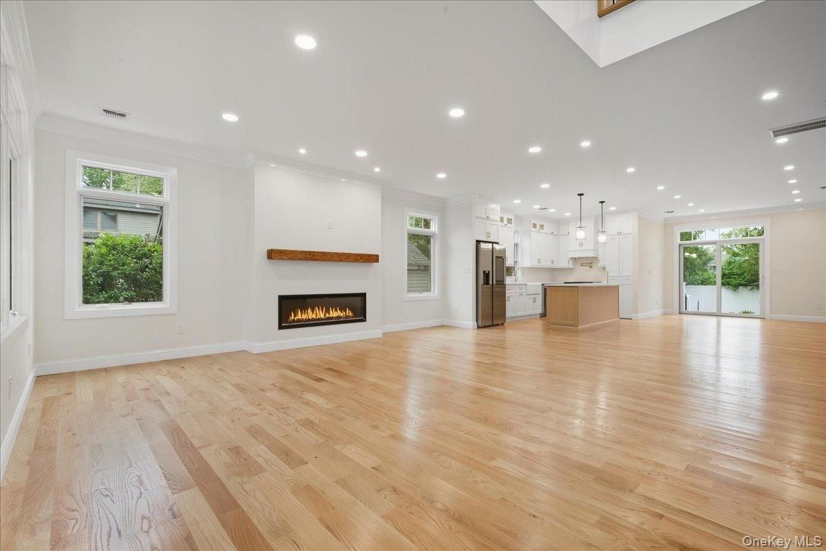 Empty room, Fireplace, Interior, Kitchen, Pendant Lights, Recessed Lighting, Stainless Steel Appliances, Wood Texture Flooring