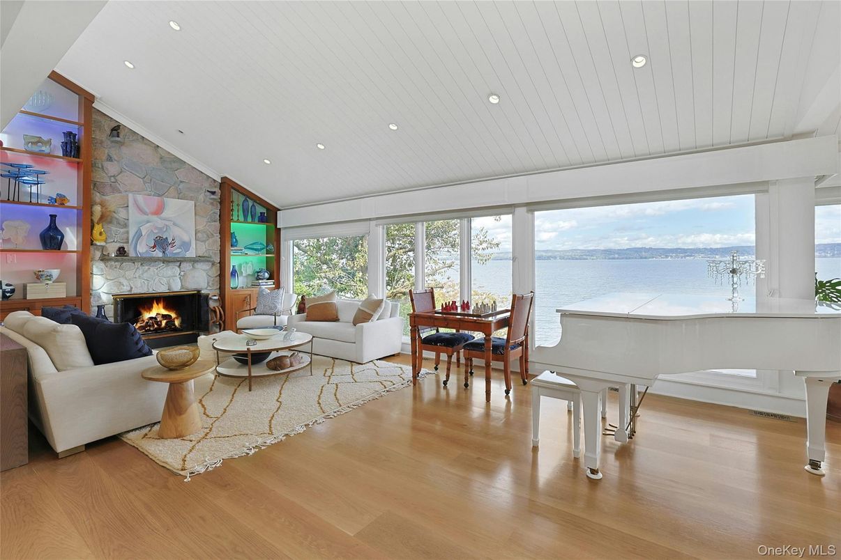 Dining room, Fireplace, Interior, Living room, Piano, Recessed Lighting, Stone Walls, Water, Wood Texture Flooring