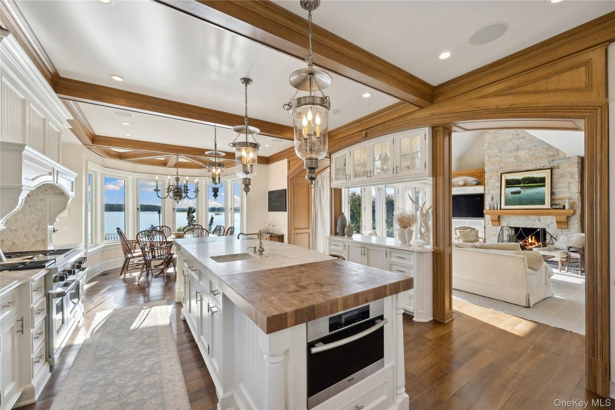 Chandelier, Dining room, Fireplace, Interior, Kitchen, Living room, Pendant Lights, Recessed Lighting, Stainless Steel Appliances, Stone Walls, Water, Wooden Beams, Wood Texture Flooring