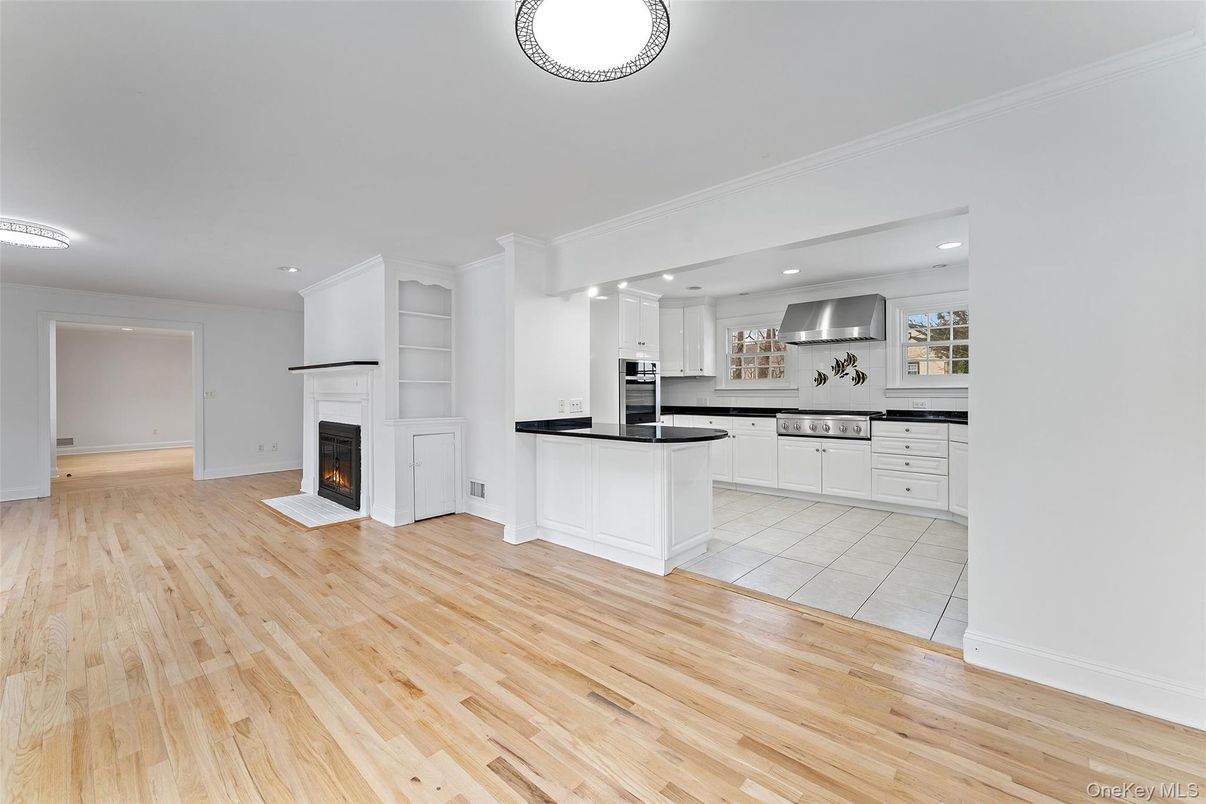 Empty room, Fireplace, Interior, Kitchen, Recessed Lighting, Stainless Steel Appliances, Wood Texture Flooring