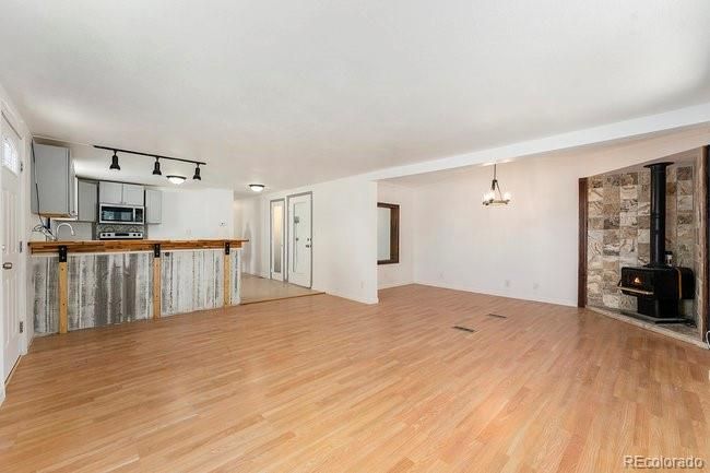 Empty room, Fireplace, Interior, Kitchen, Pendant Lights, Stainless Steel Appliances, Stone Walls, Wood Texture Flooring
