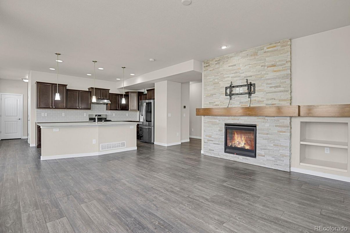 Empty room, Fireplace, Interior, Kitchen, Pendant Lights, Recessed Lighting, Stainless Steel Appliances, Stone Walls, Wood Texture Flooring