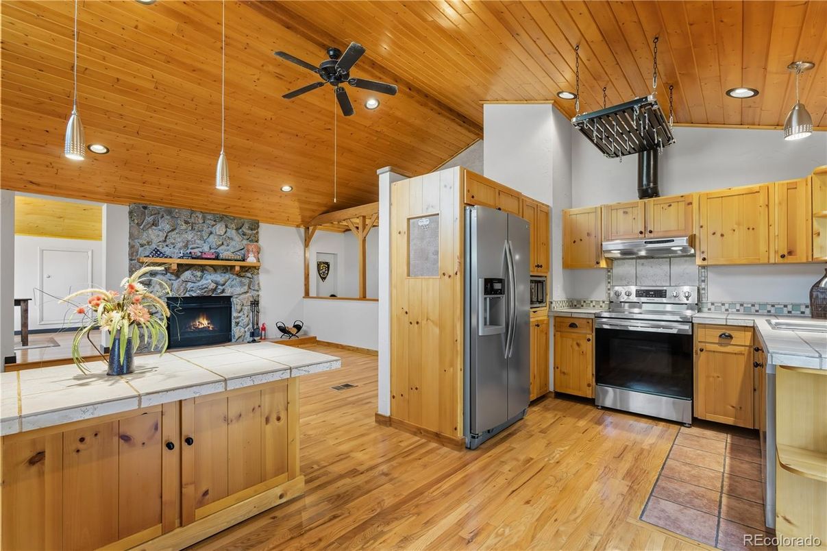 Fireplace, Interior, Kitchen, Pendant Lights, Recessed Lighting, Stainless Steel Appliances, Stone Walls, Tile Countertops, Wooden Ceilings, Wood Texture Flooring