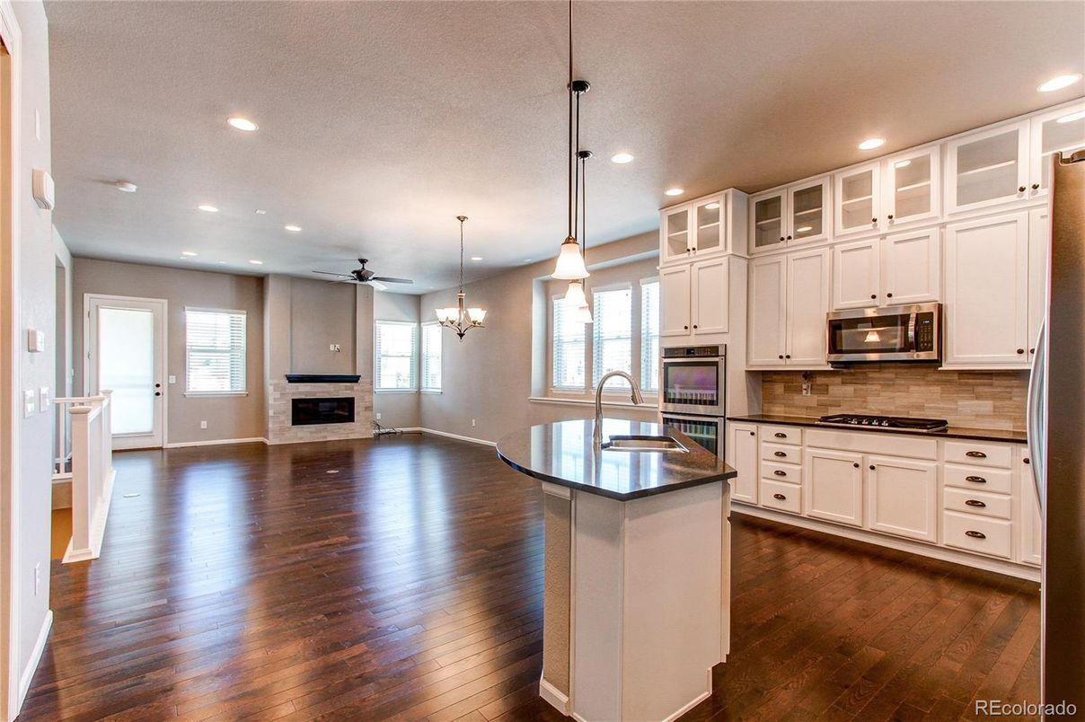 Chandelier, Empty room, Fireplace, Interior, Kitchen, Pendant Lights, Recessed Lighting, Stainless Steel Appliances, Wood Texture Flooring