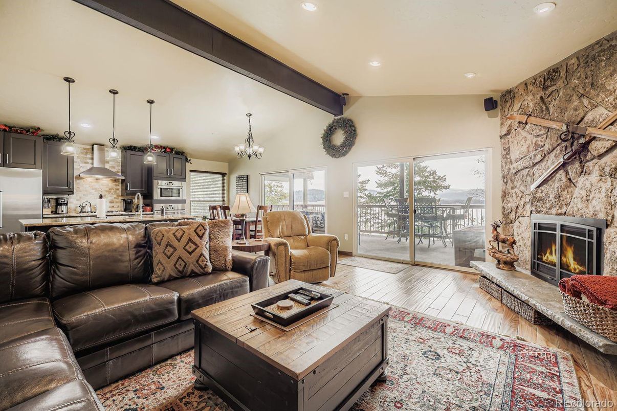 Chandelier, Fireplace, Interior, Kitchen, Living room, Pendant Lights, Recessed Lighting, Stainless Steel Appliances, Stone Walls, Wooden Beams, Wood Texture Flooring