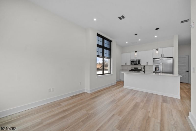 Empty room, Interior, Kitchen, Pendant Lights, Recessed Lighting, Stainless Steel Appliances, Wood Texture Flooring