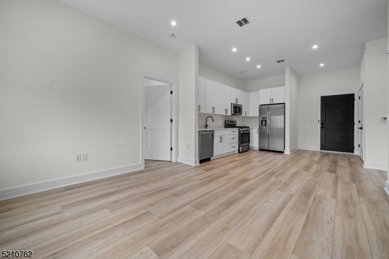 Empty room, Interior, Kitchen, Recessed Lighting, Stainless Steel Appliances, Wood Texture Flooring
