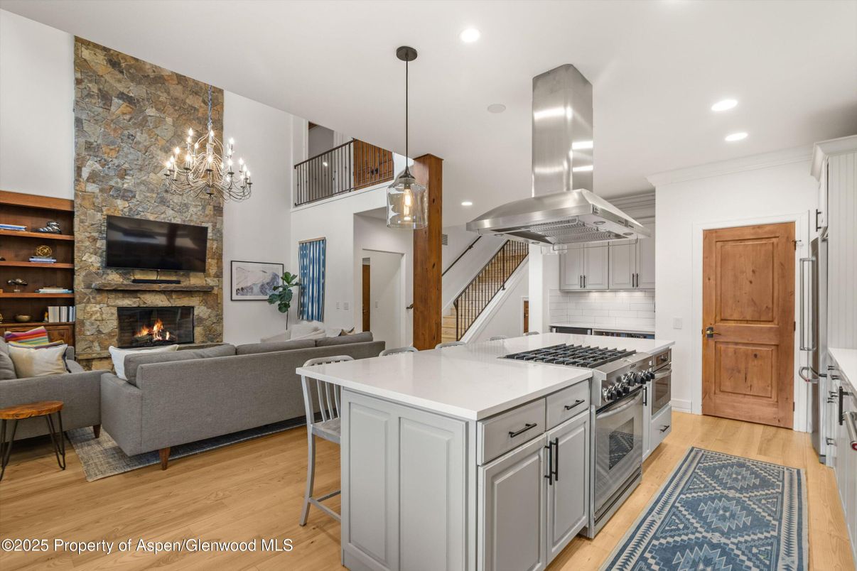 Fireplace, Interior, Kitchen, Living room, Pendant Lights, Recessed Lighting, Stainless Steel Appliances, Stone Walls, Wood Texture Flooring