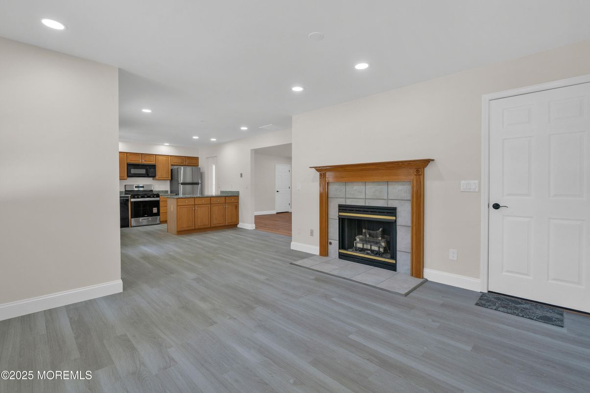 Empty room, Fireplace, Interior, Kitchen, Recessed Lighting, Stainless Steel Appliances, Wood Texture Flooring