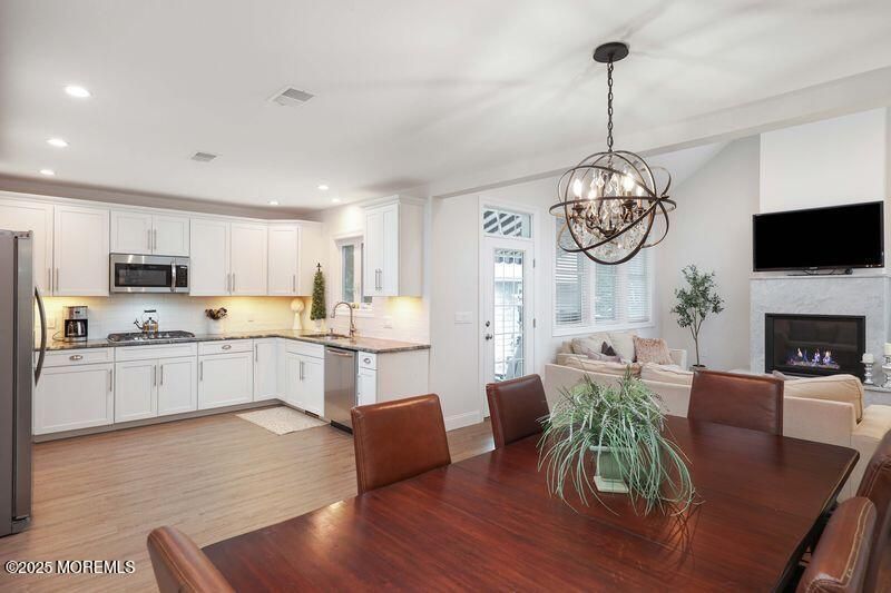 Chandelier, Dining room, Fireplace, Interior, Kitchen, Living room, Pendant Lights, Recessed Lighting, Stainless Steel Appliances, Wood Texture Flooring