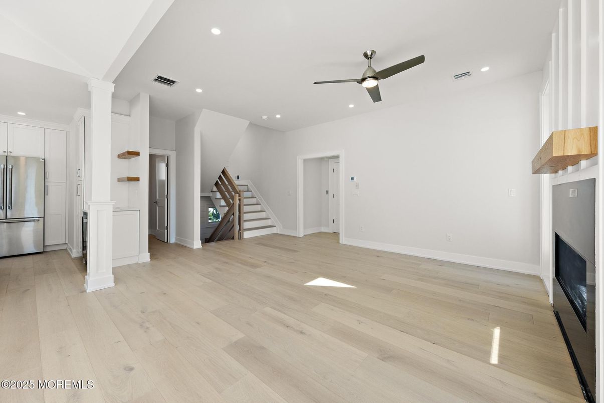 Empty room, Fireplace, Interior, Kitchen, Recessed Lighting, Stainless Steel Appliances, Wood Texture Flooring