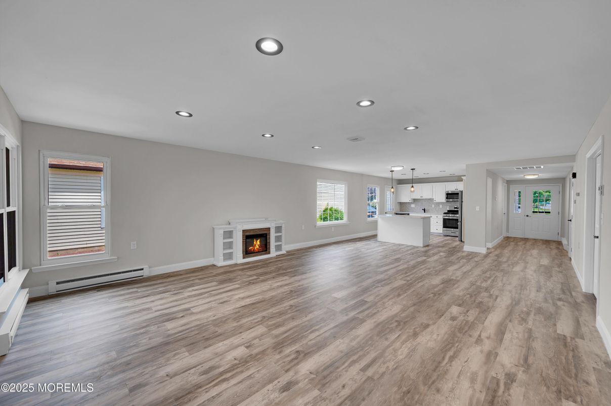 Empty room, Fireplace, Interior, Kitchen, Pendant Lights, Recessed Lighting, Stainless Steel Appliances, Wood Texture Flooring