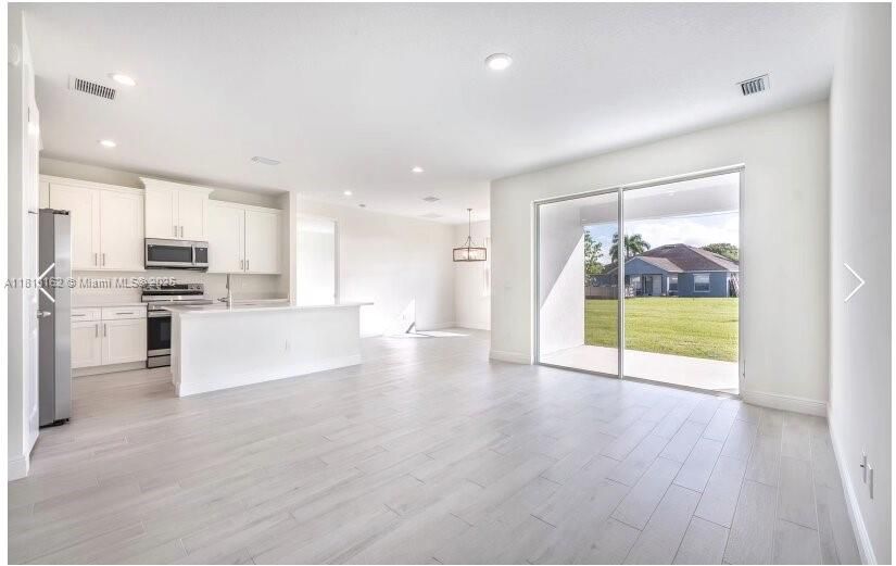 Empty room, Interior, Kitchen, Pendant Lights, Recessed Lighting, Stainless Steel Appliances, Wood Texture Flooring