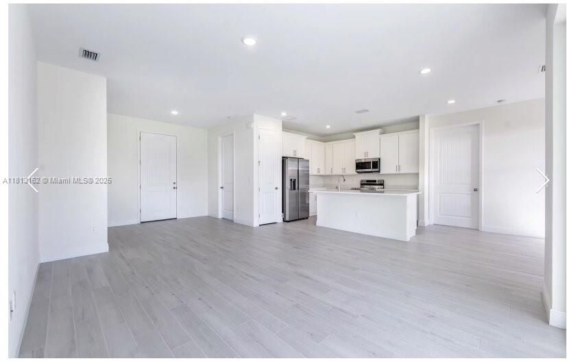Empty room, Interior, Kitchen, Recessed Lighting, Stainless Steel Appliances, Wood Texture Flooring