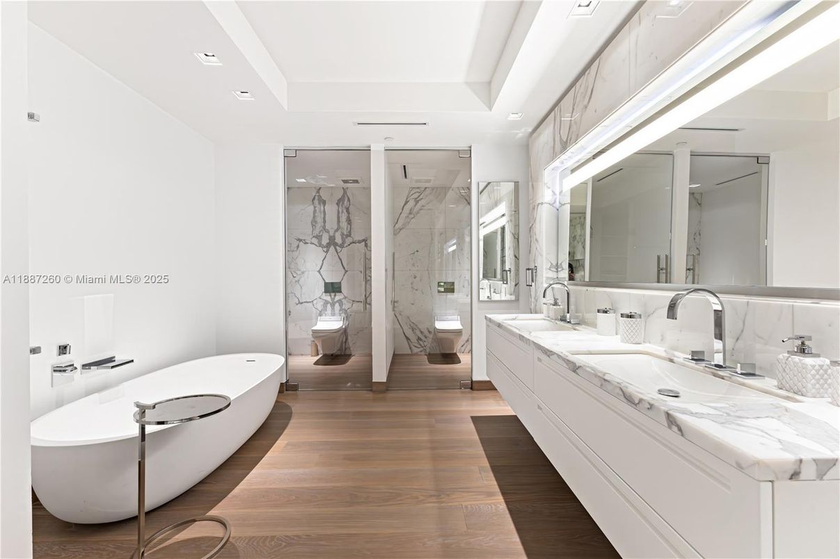 Bathroom, Dual Sink Vanities, Free Standing Baths, Glass Shower, Interior, Marble Walls, Recessed Lighting, Wood Texture Flooring