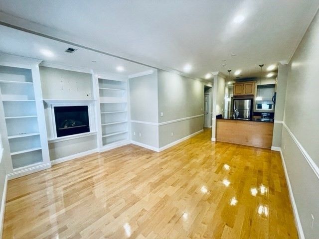 Empty room, Fireplace, Interior, Kitchen, Recessed Lighting, Stainless Steel Appliances, Wood Texture Flooring
