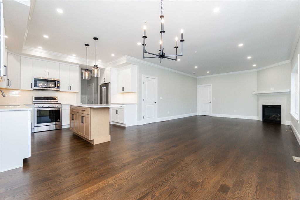 Chandelier, Empty room, Fireplace, Interior, Kitchen, Pendant Lights, Recessed Lighting, Stainless Steel Appliances, Wood Texture Flooring