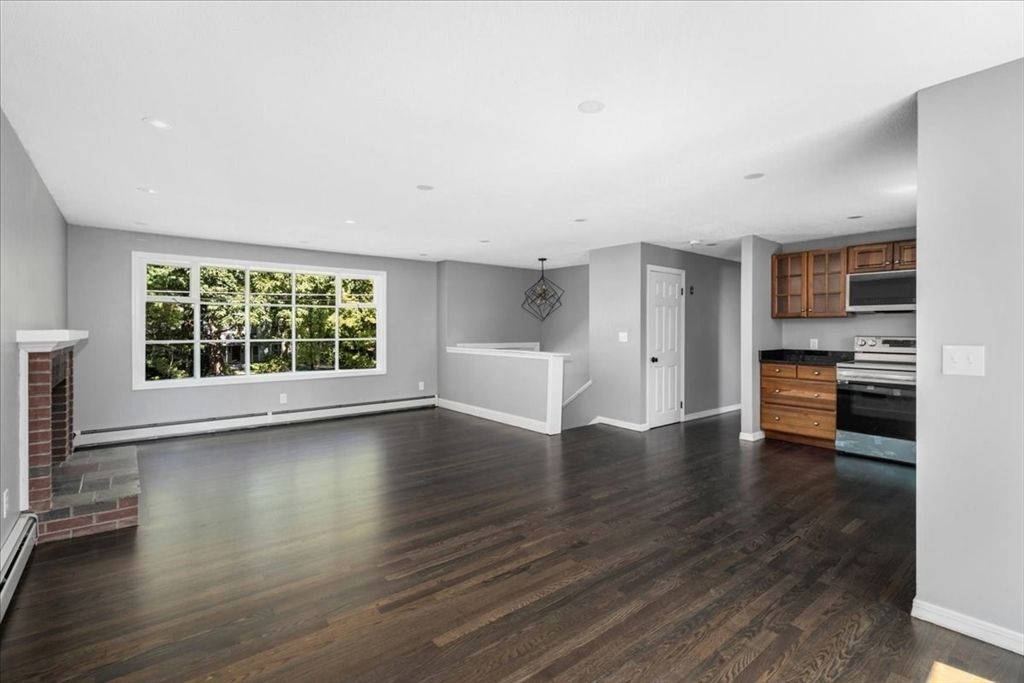 Empty room, Fireplace, Interior, Kitchen, Pendant Lights, Recessed Lighting, Stainless Steel Appliances, Wood Texture Flooring