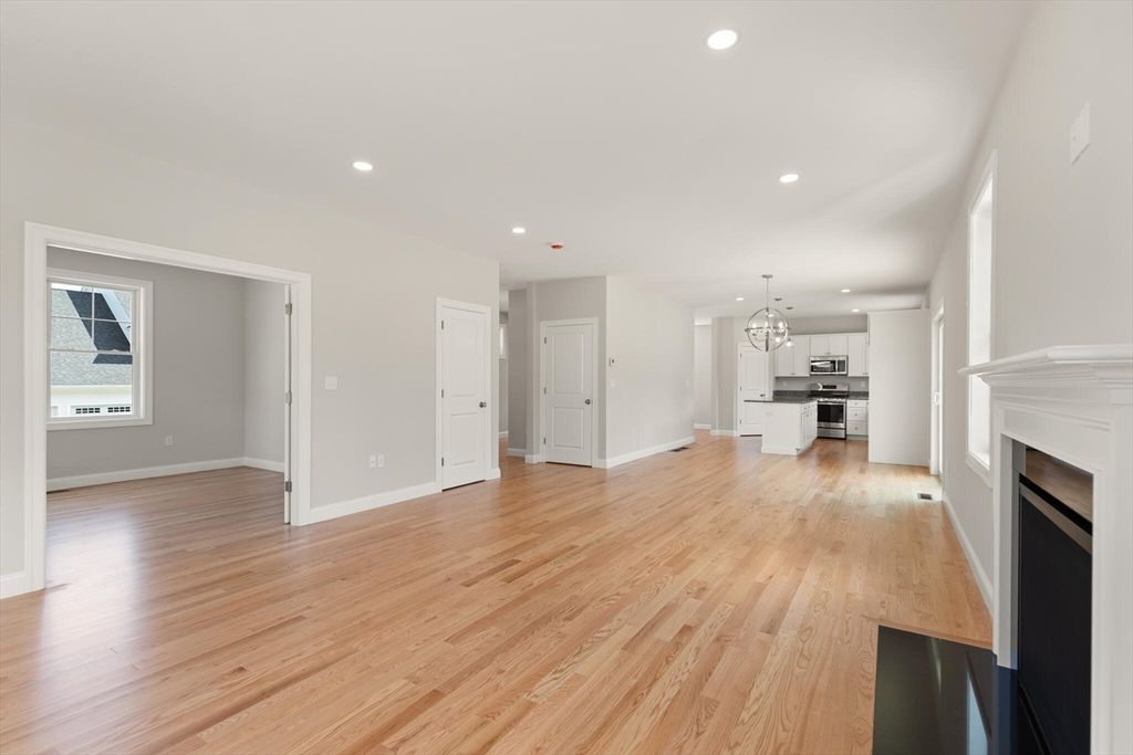Chandelier, Empty room, Fireplace, Interior, Kitchen, Pendant Lights, Recessed Lighting, Stainless Steel Appliances, Wood Texture Flooring