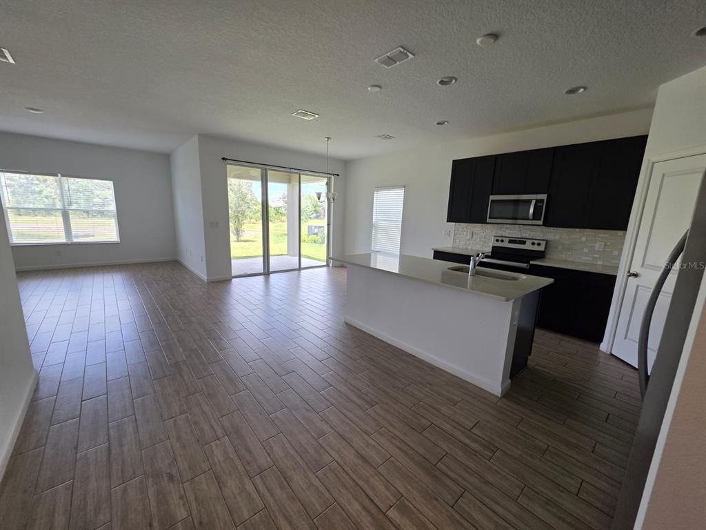 Empty room, Interior, Kitchen, Pendant Lights, Recessed Lighting, Stainless Steel Appliances, Wood Texture Flooring