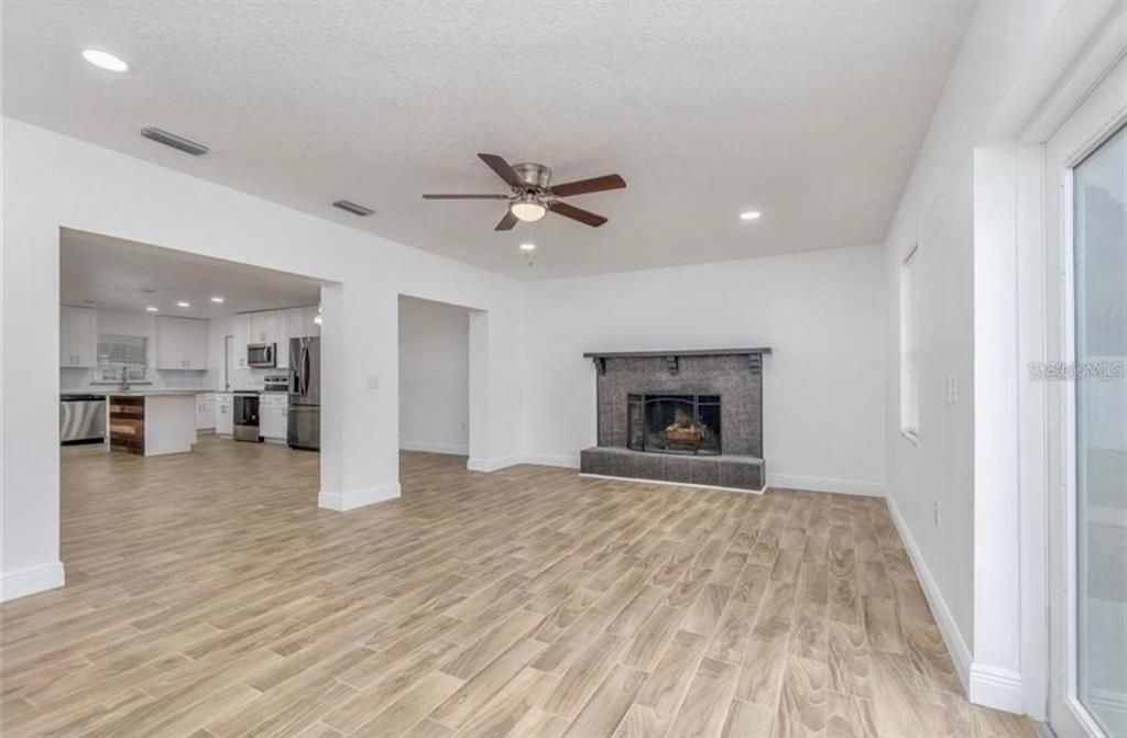 Empty room, Fireplace, Interior, Kitchen, Recessed Lighting, Stainless Steel Appliances, Wood Texture Flooring