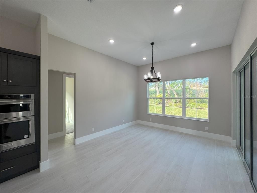 Chandelier, Empty room, Interior, Kitchen, Pendant Lights, Recessed Lighting, Stainless Steel Appliances, Wood Texture Flooring