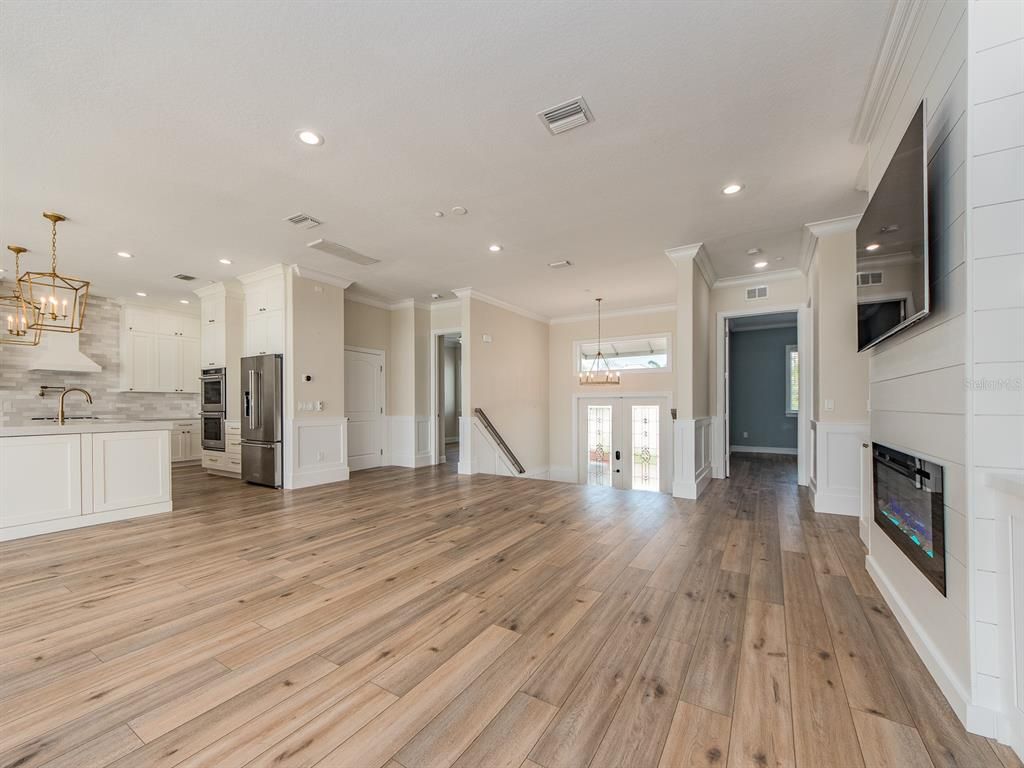 Chandelier, Empty room, Fireplace, Interior, Kitchen, Pendant Lights, Recessed Lighting, Stainless Steel Appliances, Wood Texture Flooring