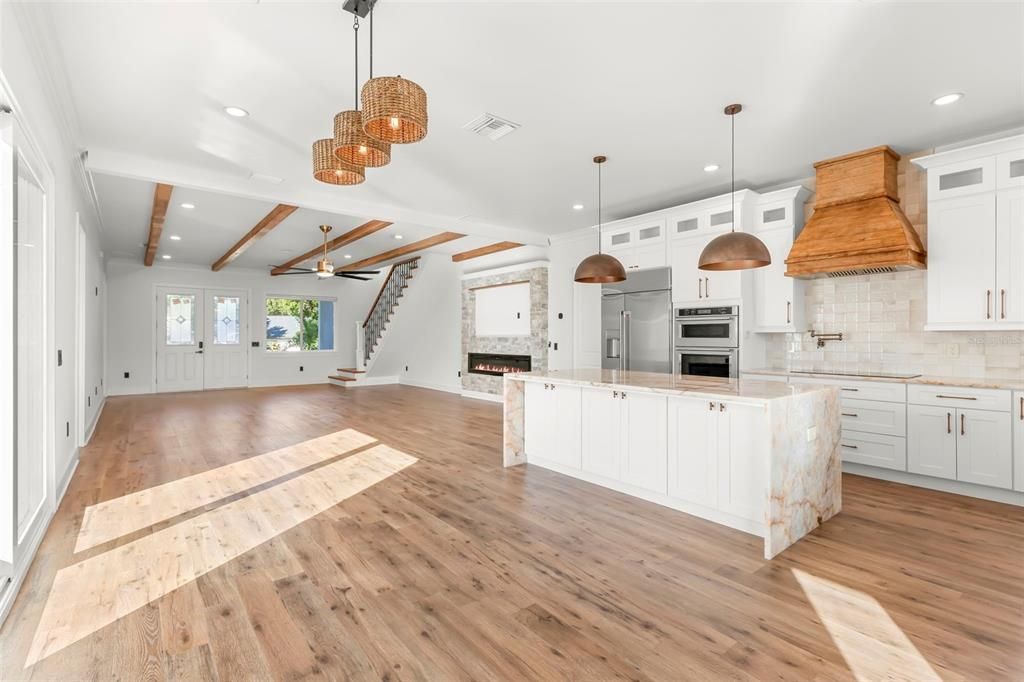 Empty room, Fireplace, Interior, Kitchen, Pendant Lights, Recessed Lighting, Stainless Steel Appliances, Wood Texture Flooring