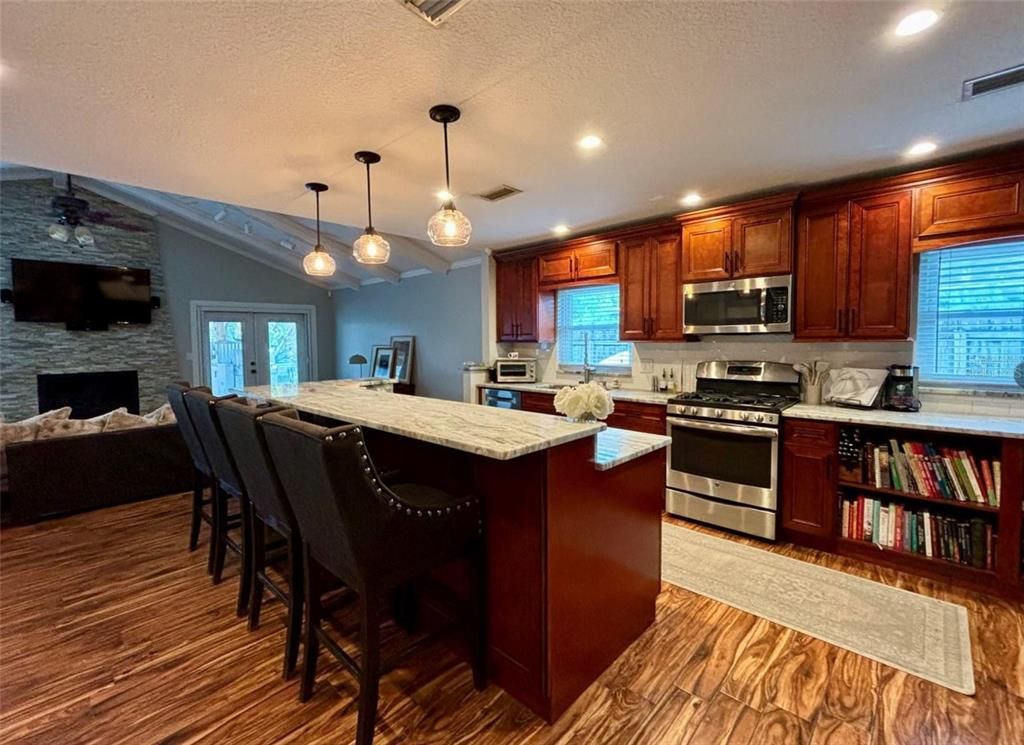 Fireplace, Interior, Kitchen, Pendant Lights, Recessed Lighting, Stainless Steel Appliances, Stone Walls, Wood Texture Flooring