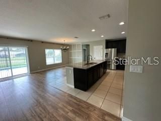 Chandelier, Empty room, Interior, Kitchen, Pendant Lights, Recessed Lighting, Stainless Steel Appliances, Wood Texture Flooring
