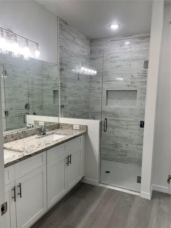 Bathroom, Dual Sink Vanities, Glass Shower, Interior, Marble Walls, Recessed Lighting, Wood Texture Flooring