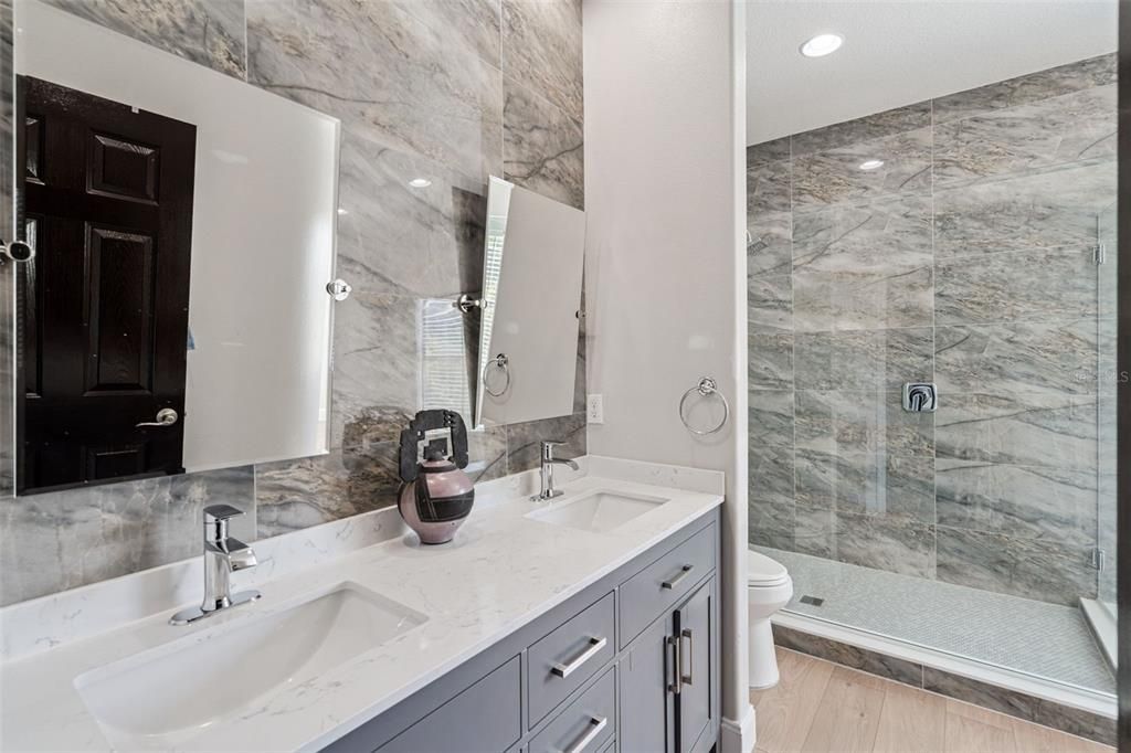 Bathroom, Dual Sink Vanities, Glass Shower, Interior, Marble Walls, Recessed Lighting, Wood Texture Flooring
