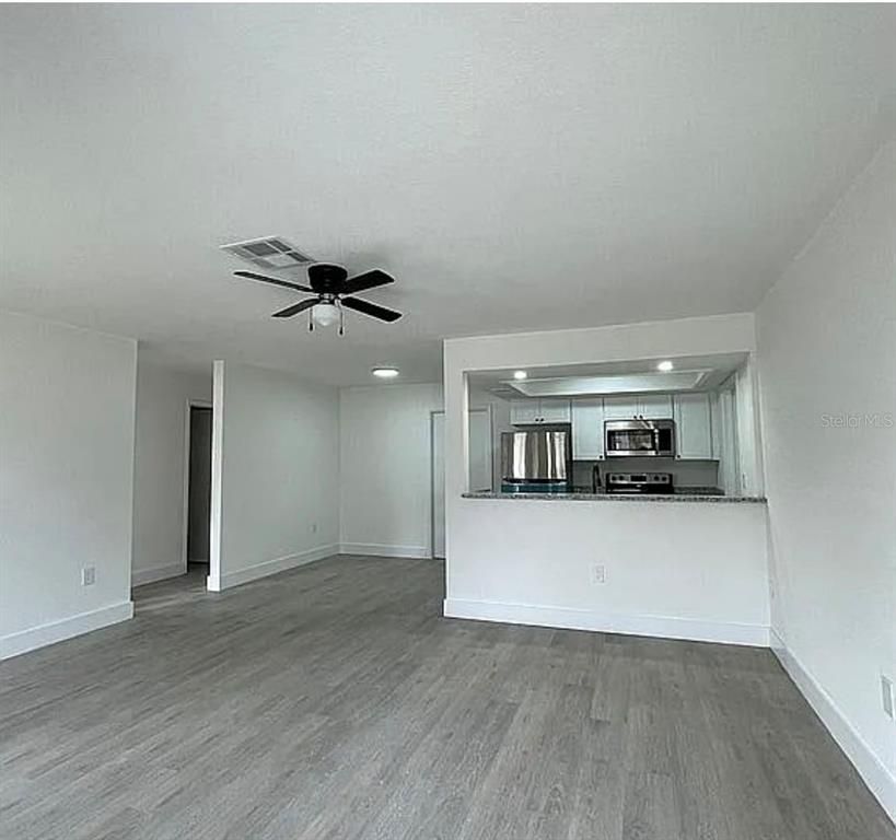 Empty room, Interior, Kitchen, Recessed Lighting, Stainless Steel Appliances, Wood Texture Flooring