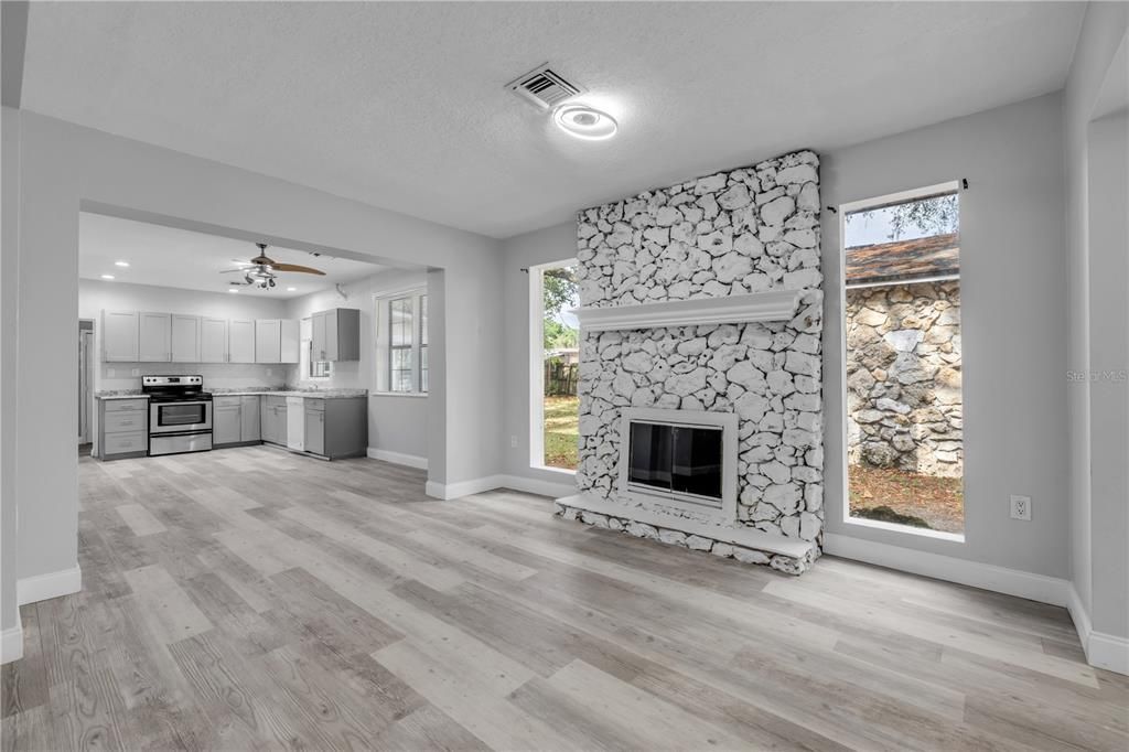 Empty room, Fireplace, Interior, Kitchen, Recessed Lighting, Stainless Steel Appliances, Stone Walls, Wood Texture Flooring