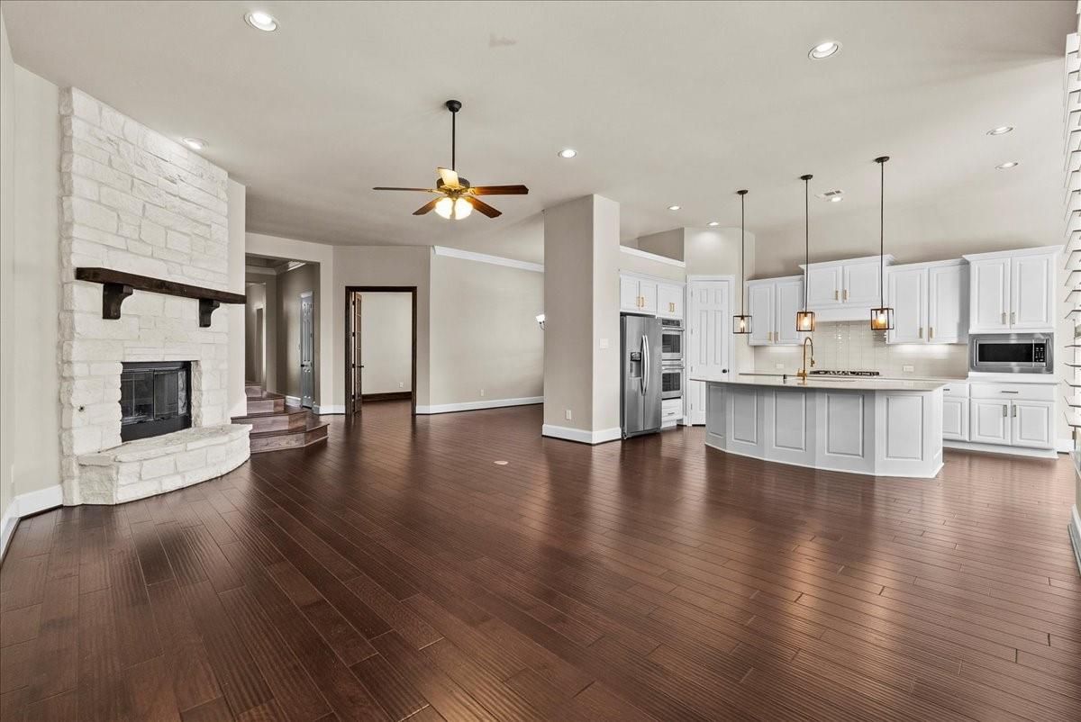 Empty room, Fireplace, Interior, Kitchen, Pendant Lights, Recessed Lighting, Stainless Steel Appliances, Stone Walls, Wood Texture Flooring
