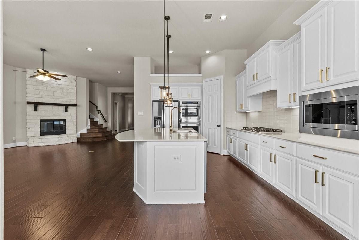 Fireplace, Interior, Kitchen, Pendant Lights, Recessed Lighting, Stainless Steel Appliances, Stone Walls, Wood Texture Flooring