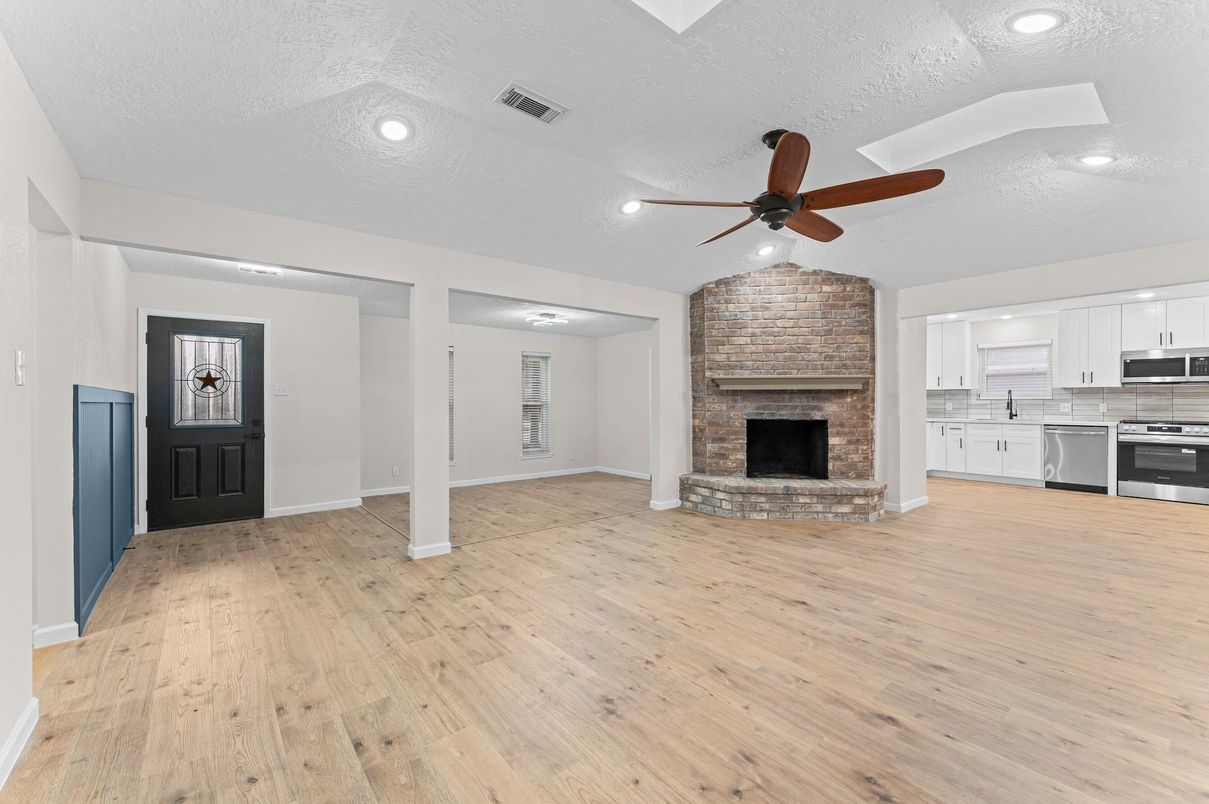 Empty room, Fireplace, Interior, Kitchen, Recessed Lighting, Stainless Steel Appliances, Stone Walls, Wood Texture Flooring