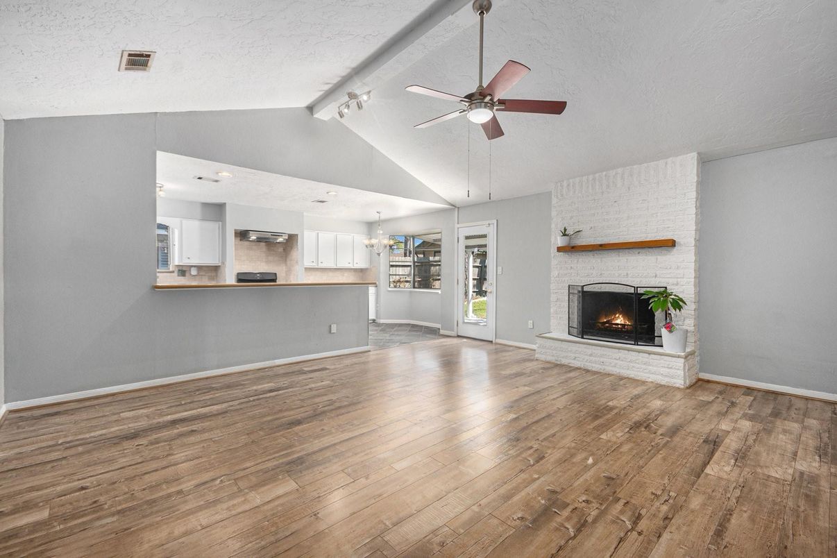 Chandelier, Empty room, Fireplace, Interior, Kitchen, Recessed Lighting, Stainless Steel Appliances, Wood Texture Flooring