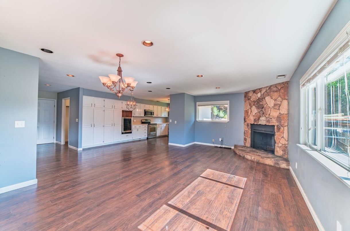 Chandelier, Empty room, Fireplace, Interior, Kitchen, Recessed Lighting, Stainless Steel Appliances, Stone Walls, Wood Texture Flooring