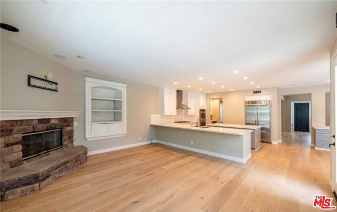 Empty room, Fireplace, Interior, Kitchen, Recessed Lighting, Stainless Steel Appliances, Wood Texture Flooring