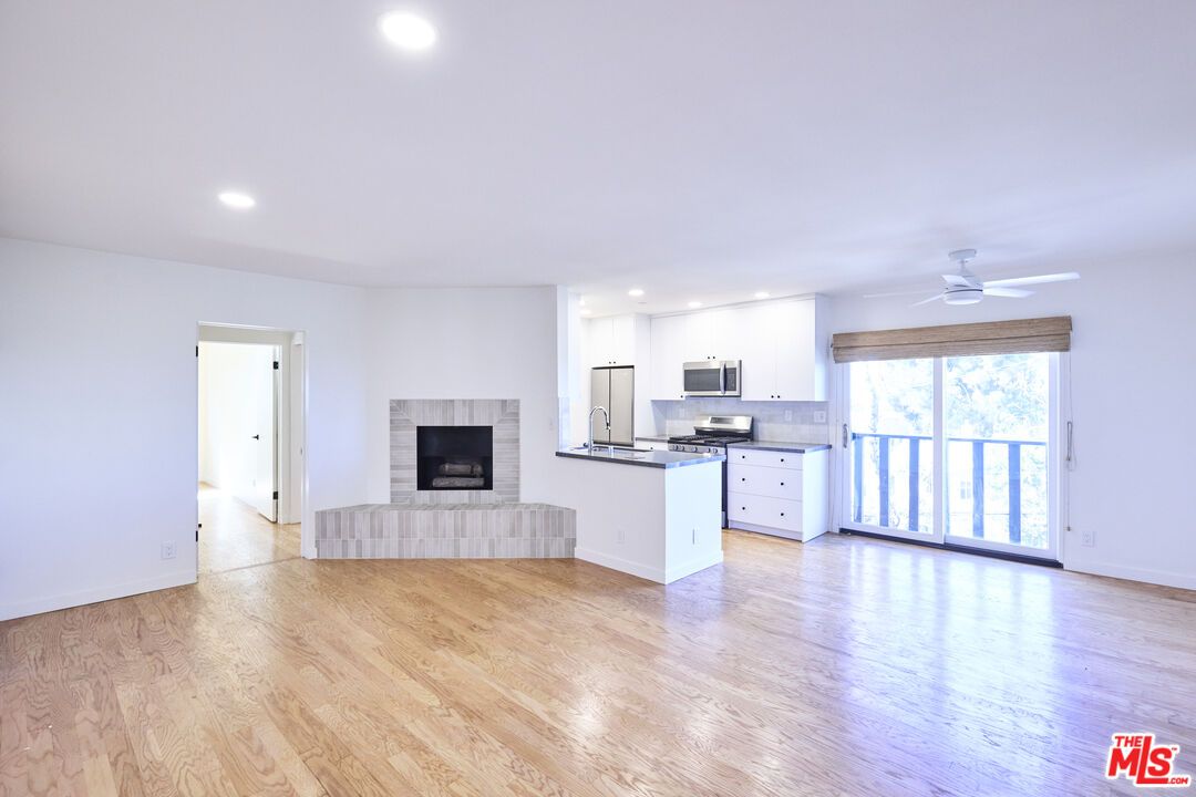 Empty room, Fireplace, Interior, Kitchen, Recessed Lighting, Stainless Steel Appliances, Wood Texture Flooring