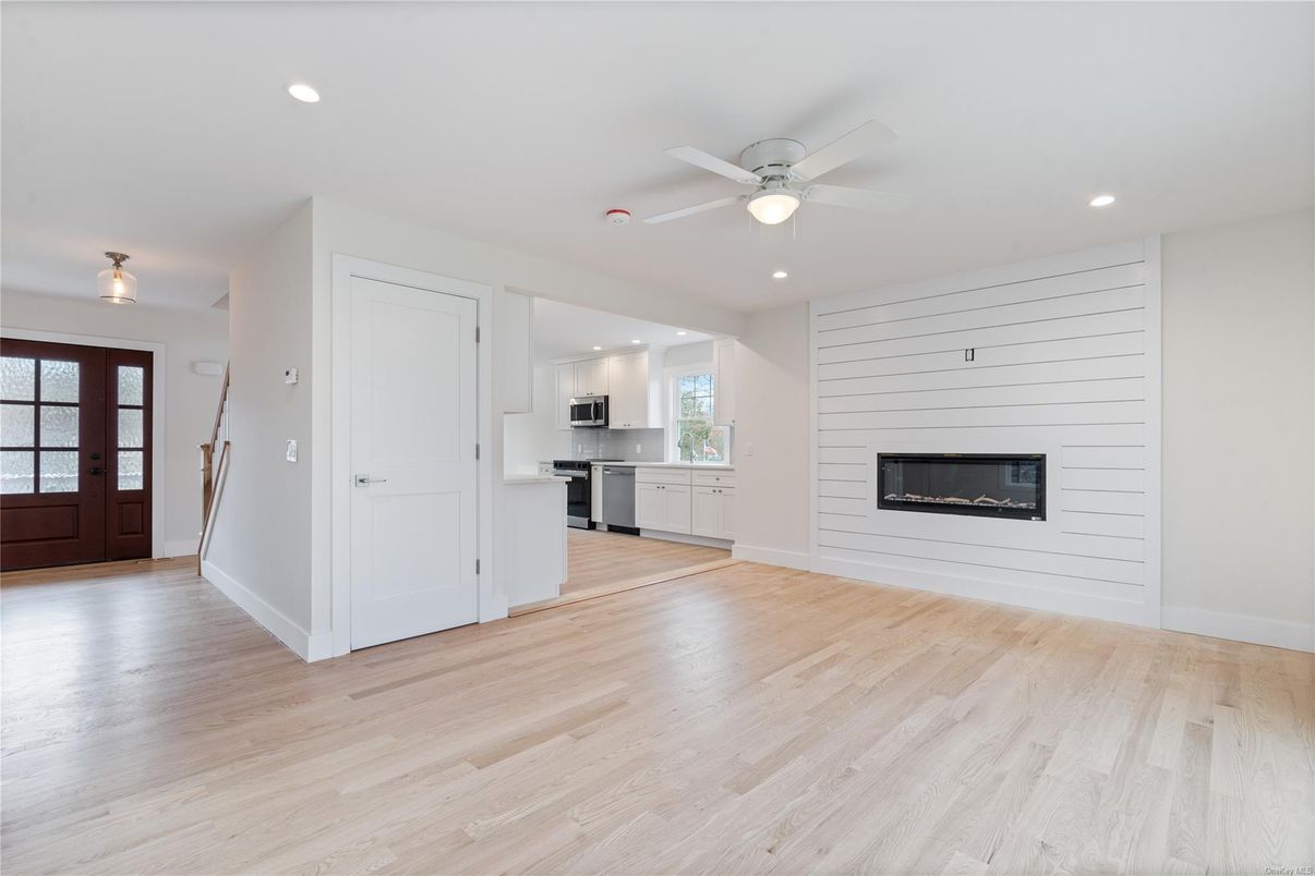 Empty room, Fireplace, Interior, Kitchen, Recessed Lighting, Stainless Steel Appliances, Wood Texture Flooring