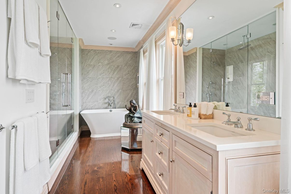 Bathroom, Dual Sink Vanities, Free Standing Baths, Glass Shower, Interior, Marble Walls, Recessed Lighting, Wood Texture Flooring
